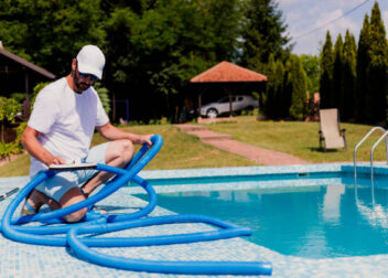 photo d'un homme qui entretien sa piscine avec un tube bleu