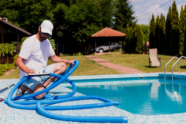 photo d'un homme qui entretien sa piscine avec un tube bleu