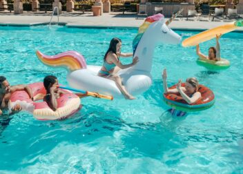 Amis qui s'amuse dans une piscine avec des bouées et des pistolets à eau