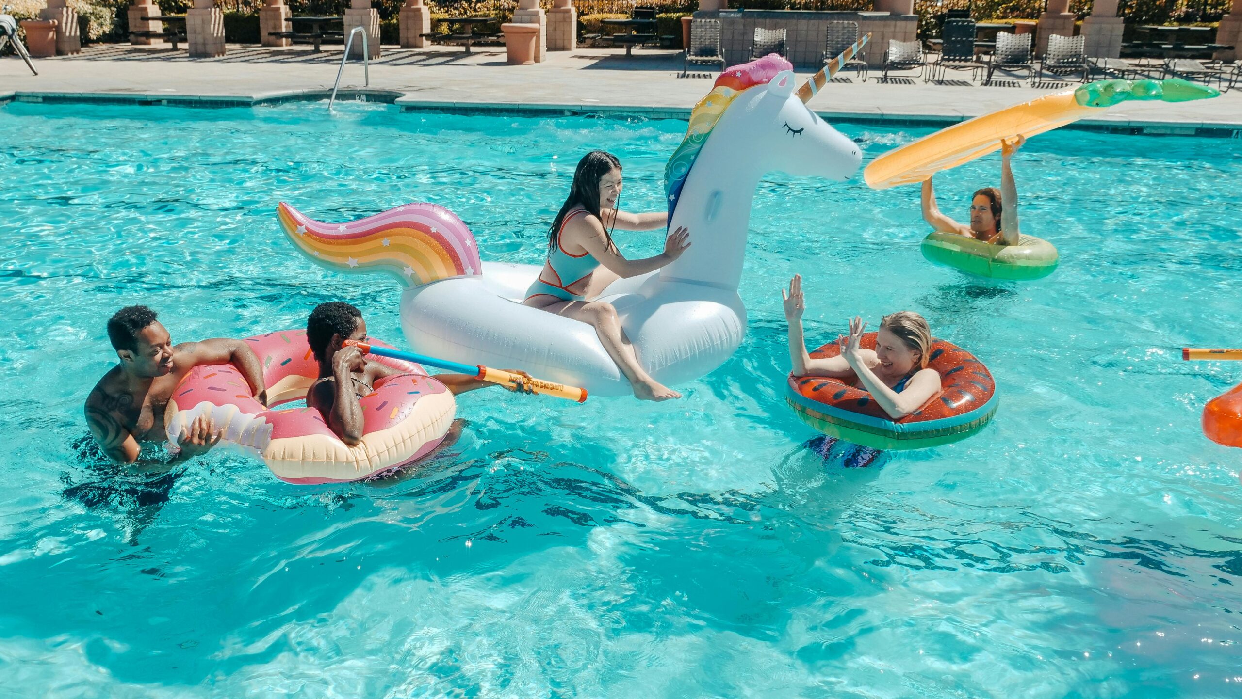 Amis qui s'amuse dans une piscine avec des bouées et des pistolets à eau